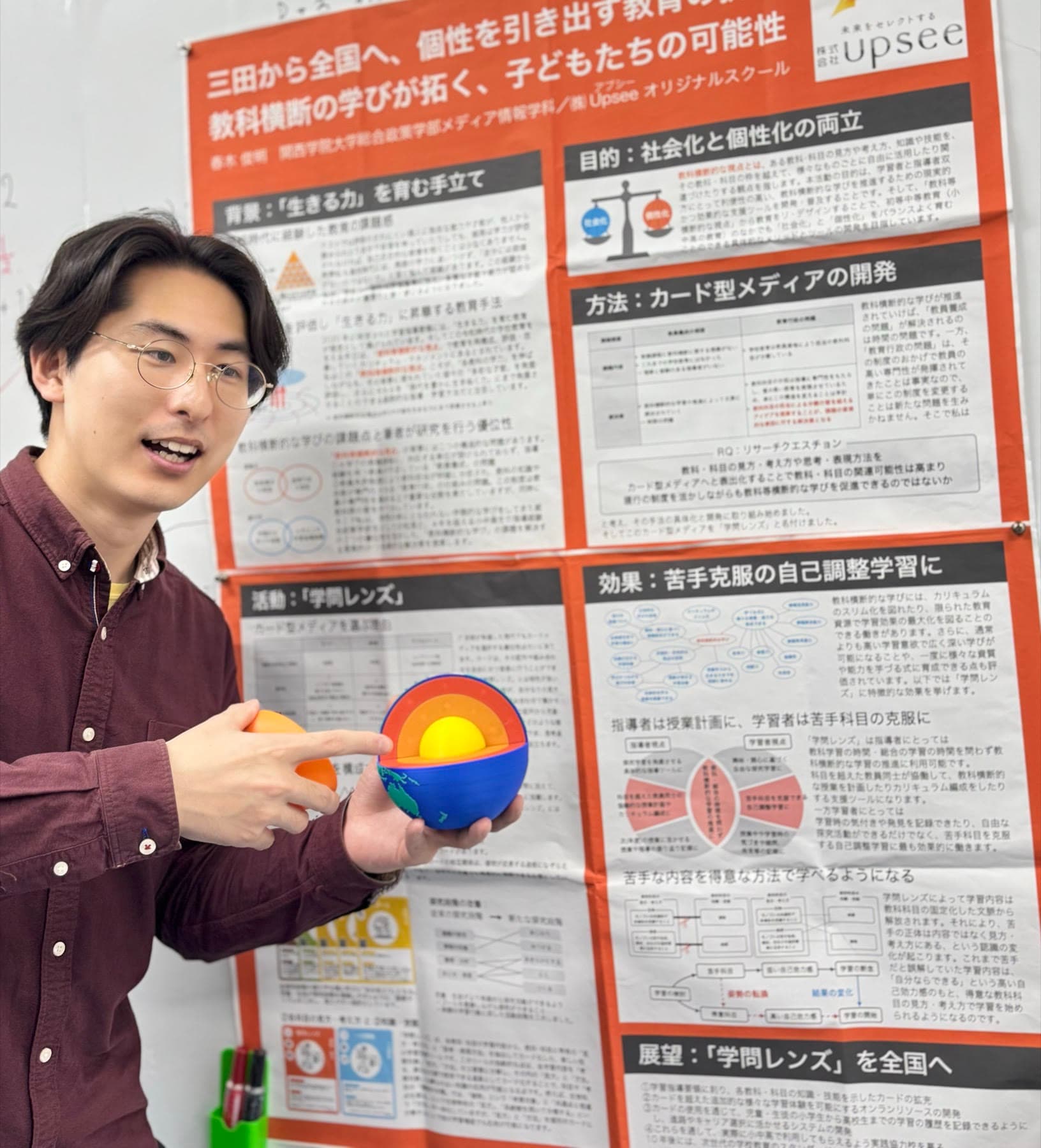 研究ポスターの前で学問レンズを説明する代表・春木俊明