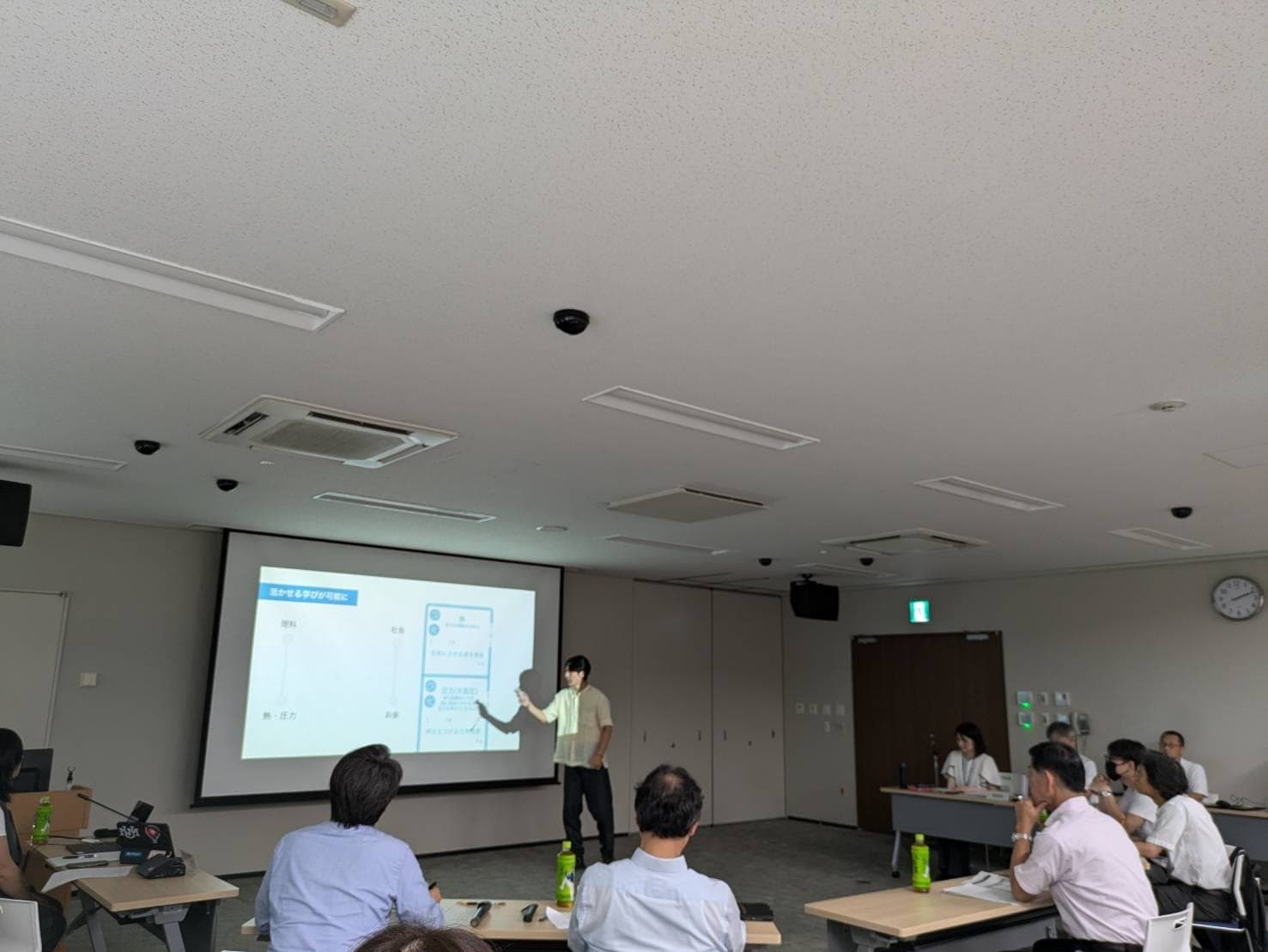 会場の前方でプレゼンテーションをする代表