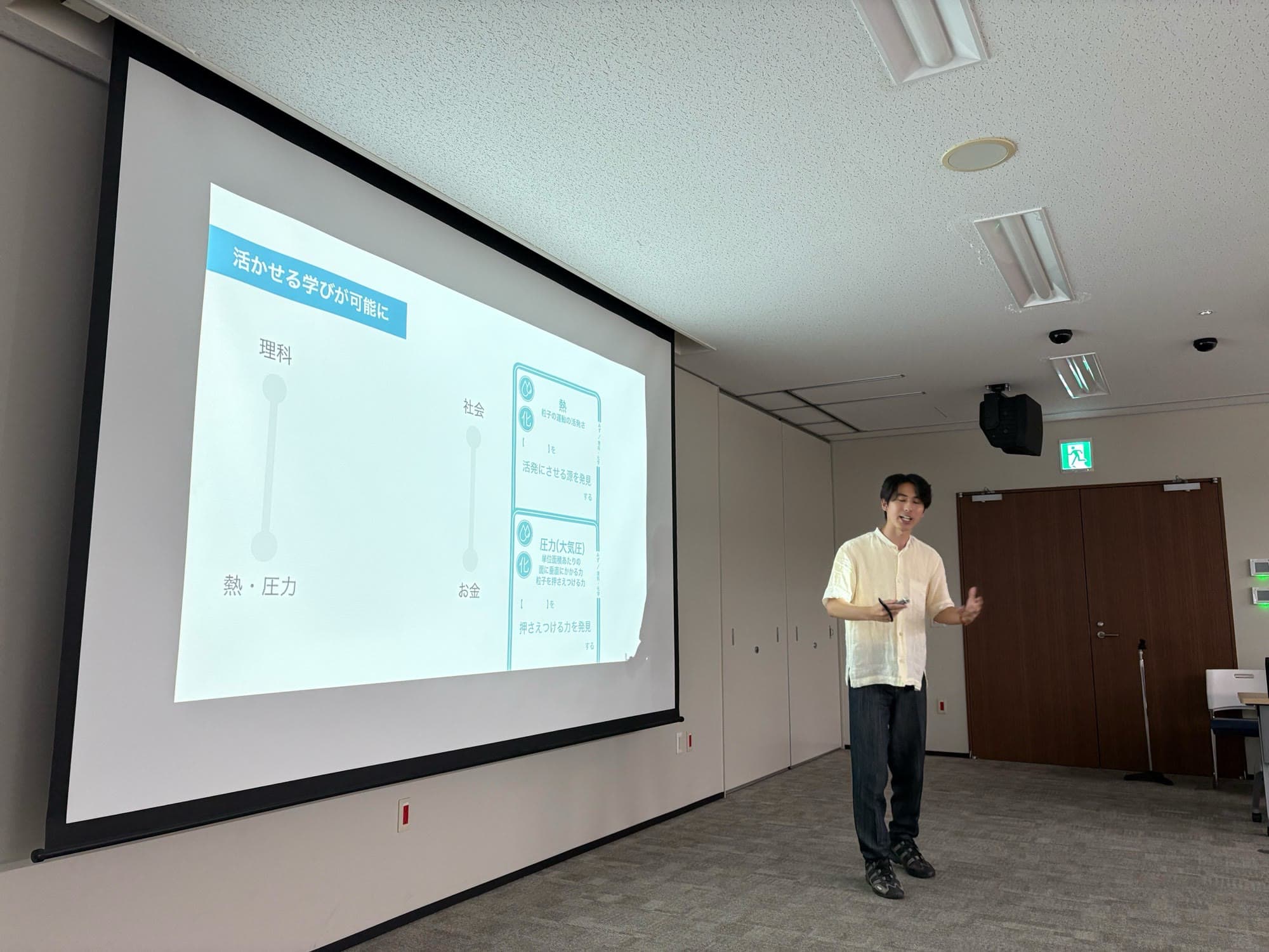 セミナー会場でスライドを使って話す代表